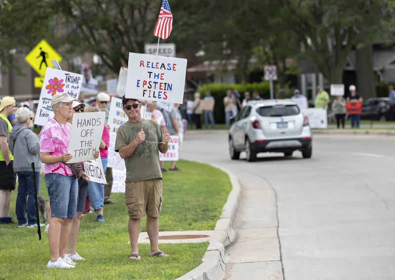 Protesters hoist signs Thursday, July 17, 2025, along East Fourth Street in Sterling for the “Good Trouble Lives On” protest.
