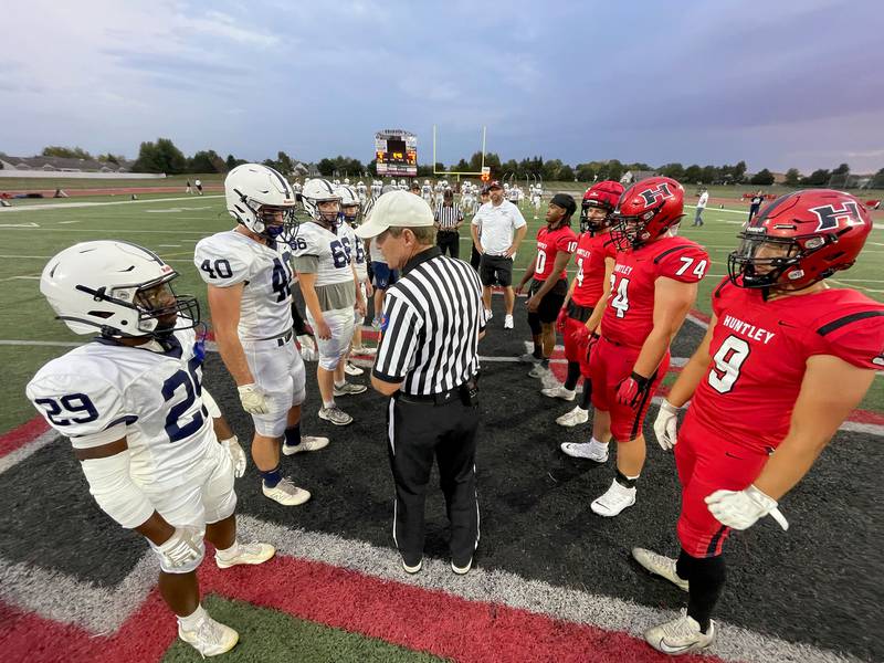 Elias Berthelsen, far left, and the Trojans of Cary-Grove line up for the pregame coin toss in varsity football at Huntley High School in Huntley on Friday, Sept. 19, 2025.