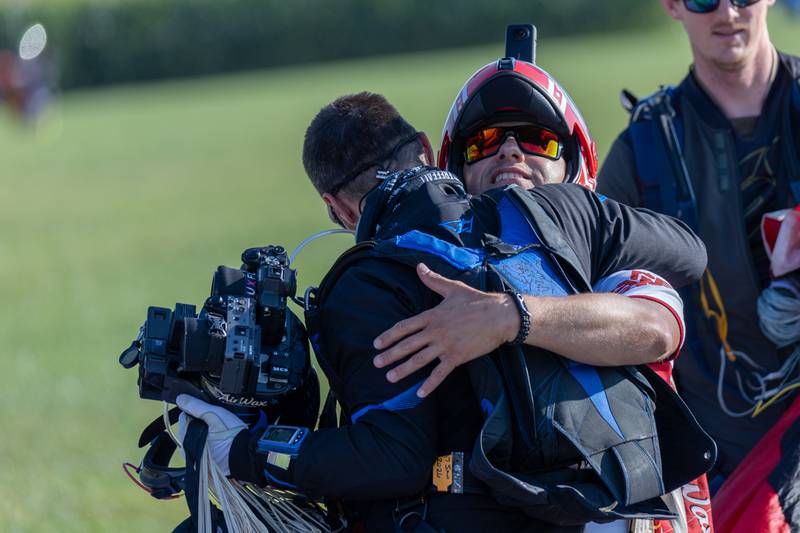(from left) Evan Cowie and Greg Crozier hug after successfully landing in drop zone on Friday, Aug 22, 2025 above Skydive Chicago in Ottawa.