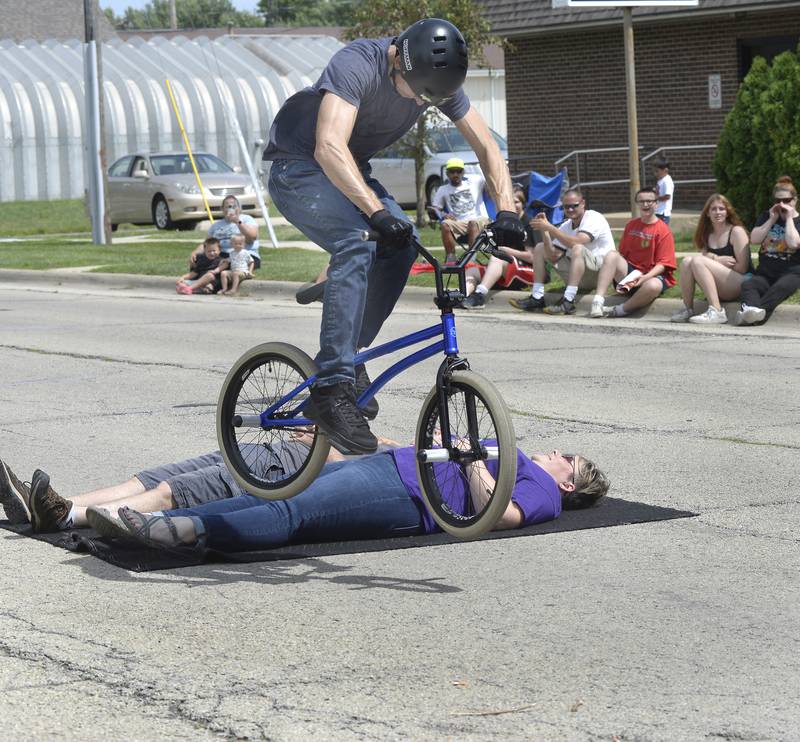 Matt Wilhelm, winner of the USA National Championship and the No. 1 ranked BMX Flatland Rider in the United States, leaps his bike over two volunteers Thursday, July 28, 2022, during a show at the Reddick Library in Ottawa.