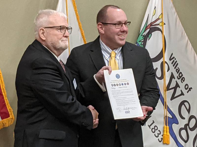 Oswego Village President Ryan Kauffman, right, signed a statement of support for the National Guard and Reserve following a presentation by Doug Wallace, left, the Northern Illinois chairman of the Employer Support of the Guard and Reserve, at the Jan. 7 Committee Of The Whole meeting.