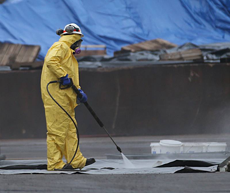 A worker in a hazmat suit sprays down a tarp at Carus Chemical on Tuesday, Jan. 17, 2023 in La Salle.
