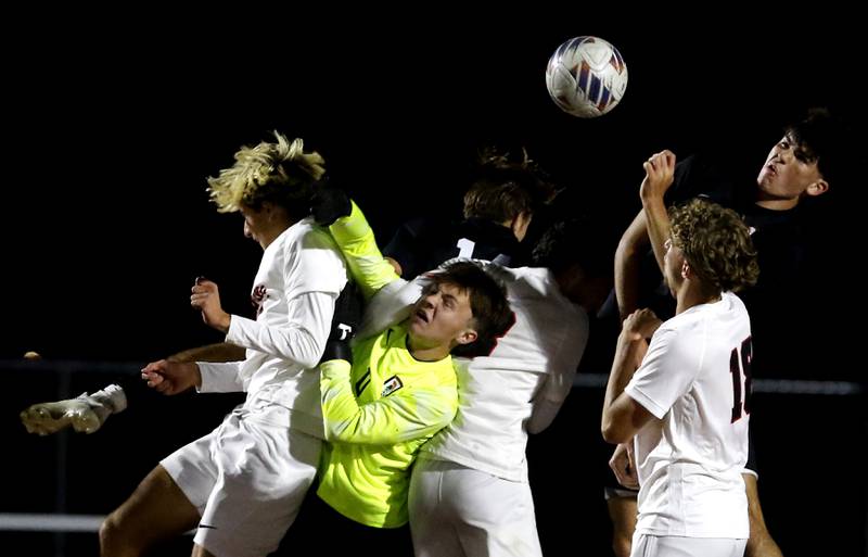 McHenry goalkeeper Auggie Arnold is sandwiched between Huntley's Cody Hammer (left) and Finley Williams as he tries to knock the ball away during a Fox Valley Conference boys soccer match on Thursday, Oct. 9, 2025, at McCracken Field in McHenry.