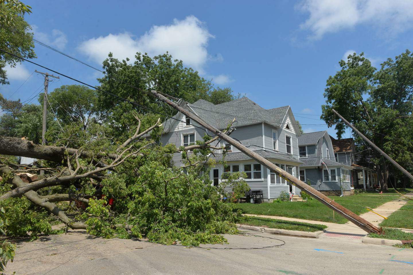 A large tree was blown over and electric poles damaged  by Friday's early morning storm at the corner of Van Buren and W. Fourth Street in Dixon. Zachary Taylor's home, pictured here, escaped major damage but the tree crushed his van. ComEd workers were dispatched to the area to repair damaged electrical lines and poles to restore power to residents in the area as temperatures climbed into the mid-90s.