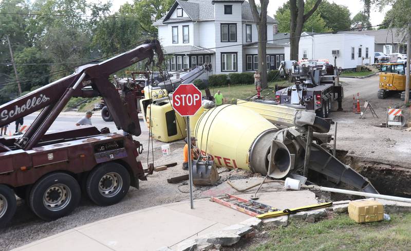 Crews with Scholles Body Shop use tow trucks to lift a cement truck out of a sinkhole on Tuesday, Sept. 2, 2025 at the intersection of Pulaski Street and 6th Streets in Peru.
