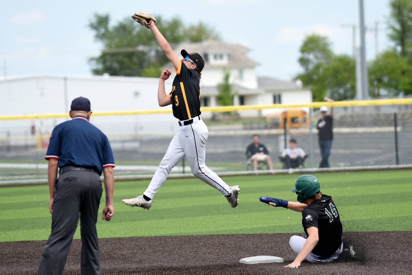 Herscher's Alec Nicholos (3) leaps to field a throw at second base as Bishop McNamara's Callaghan O'Connor slides in during the Class 2A Herscher Regional championship Saturday, May 24, 2025.