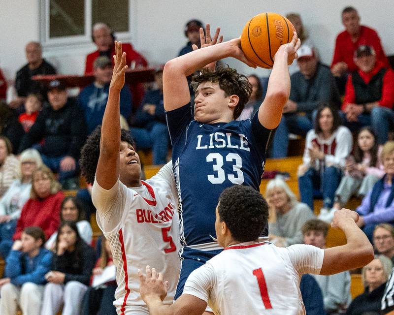 Lisle's Noah Nigro (33) holds ball over head looking for pass as Lavontae Horton (5) of Streator and teammate Layzeric Moton (1) guard on Wednesday, Feb. 18, 2026 at Streator High School in Streator.