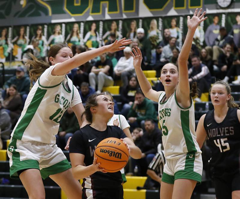 Prairie Ridge's Zoe Nanos (center) drives to the basket between \Crystal Lake South's Gaby Dzik (left) and Tessa Melhuish (right) during a Fox Valley Conference girls basketball game on Friday, Dec. 13, 2024, at Crystal Lake South High School.
