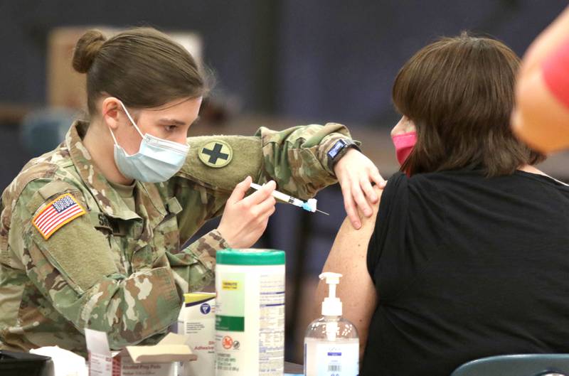 A member of the Illinois National Guard administers a dose of the COVID-19 vaccine during the DeKalb County Health Department clinic Thursday at Sandwich High School.