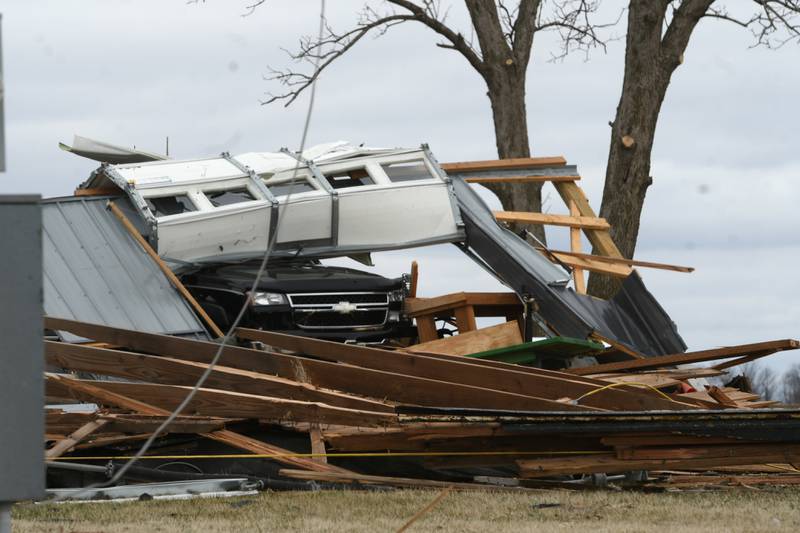 A truck is covered in debris when this garage, located across Illinois 64 from Lanark Family Farms, was destroyed by Friday's storm.