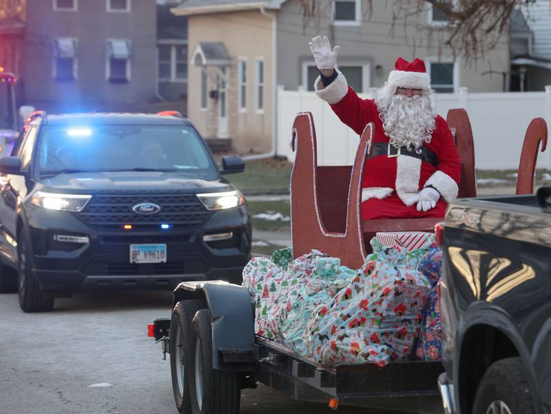 Santa waves near the intersection of 2nd and Calhoun Street as he delivers gifts to over 120 kids through the through Blue and Red Christmas for Kids on Friday, Dec. 19, 2025 in Peru. The Christmas program was established in 2013 by the Peru police and fire departments. It donates more than gifts to children in need.