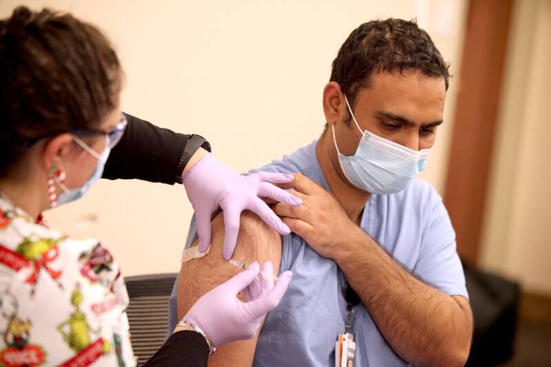 Andy Dhanoa of South Elgin, a respiratory therapist at Edward Hospital in Naperville, is the first employee to be administered the Pfizer COVID-19 vaccine on Dec. 17 by nurse Nikki Carini-Wardecki.