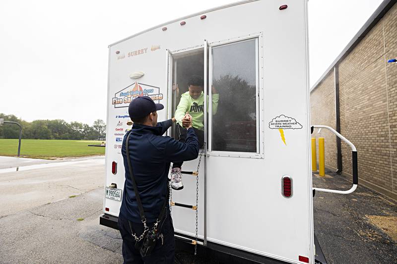 Dixon City firefighter Josh Shipman helps third grader Kayden Hines through the window of the fire safety house during a drill at Jefferson School Thursday, Oct. 12, 2023.