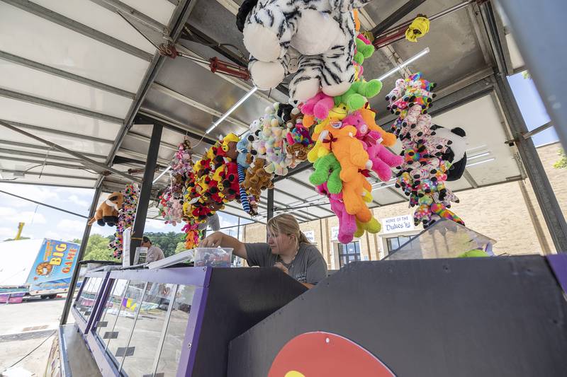 Mariah Wilson prepares a booth Tuesday, July 1, 2025, for the Petunia Fest carnival. Booths and rides are set up in front of Dixon High School. The carnival will be open from Wednesday to Sunday.