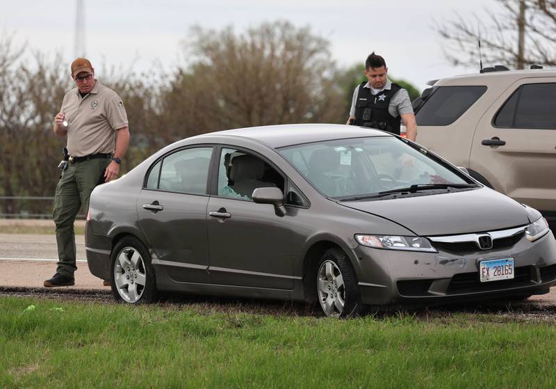 Law enforcement officials look into a Honda sedan with a shattered window in the westbound lanes of Interstate 88 Monday, April 27, 2026, as they investigate an incident on I-88 just west of Keslinger Road in Maple Park.