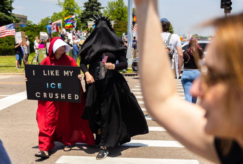 Jenny Golden wears a handmaids outfit and walks with Amy Bruederle in a “Mourning Statue of Liberty’s” outfit during a “No Kings Day” Protest against President Donald Trump’s policies along South Randall Road in Geneva on Saturday, June 14, 2025.