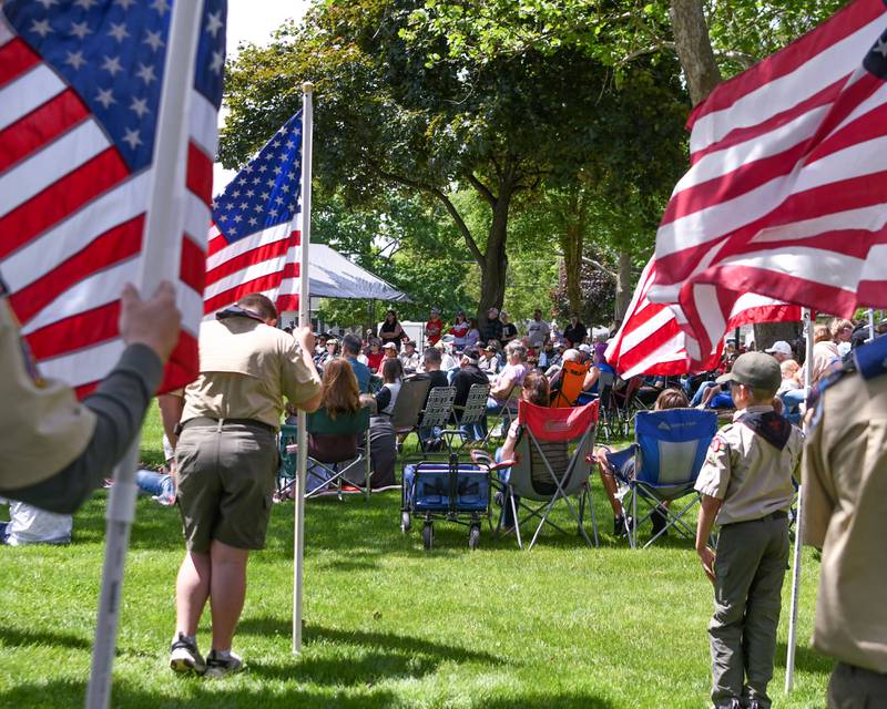 Attendees listen to Masters Sargent Devin Persaud speak during the Memorial Day event as Scout members hold American Flags on Monday May 26, 2025, held at Town Square Park in Yorkville.