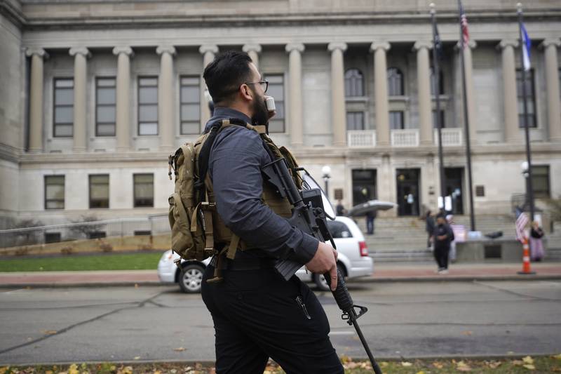 A protester carries a rifle outside the Kenosha County Courthouse, Wednesday, Nov. 17, 2021 in Kenosha, Wis., during the Kyle Rittenhouse murder trial. Rittenhouse is accused of killing two people and wounding a third during a protest over police brutality in Kenosha, last year. (AP Photo/Paul Sancya)
