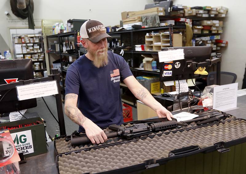 Brad Bauch, a salesperson at Marengo Guns puts a AR-15 in a case Wednesday, Jan. 18, 2023, at Marengo Guns. The McHenry County gun shop is among a group of plaintiffs challenging the constitutionality of Illinois’ ban on semiautomatic weapons and large-capacity magazines that took effect last week.