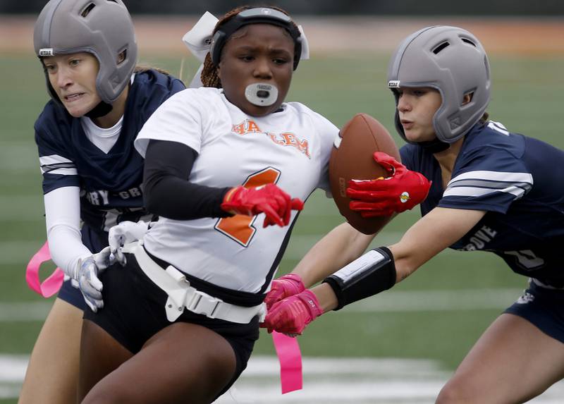 Cary-Grove's Penelope Olsen (left) and Gabriella McMorris try to grab the flags of Harlem’s Hari Young during an IHSA McHenry Sectional semifinal girls flag football game on Monday, Oct. 13, 2025, at McCracken Field in McHenry.
