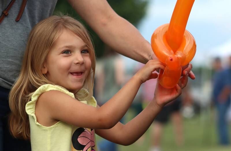 McKinley Samp, 4, of Marengo, receives a balloon toy Saturday, July 2, 2022, during the Red, White and Blue Food Truck FEASTival at Milky Way Park in Harvard.