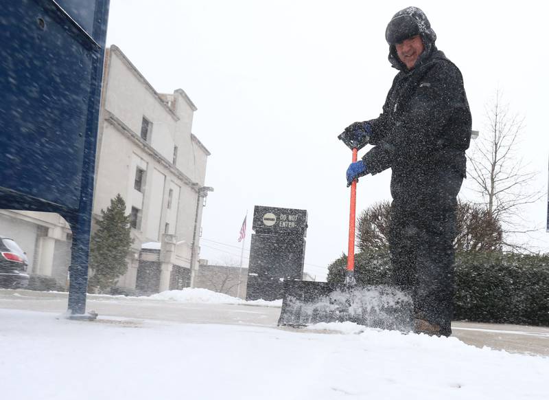 Nick Sham shovels snow off a portion of a sidewalk in front of La Salle State Bank on Wednesday, Feb. 12, 2025 downtown La Salle.