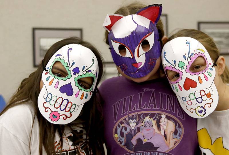 Peyton Flores, 9, Faelynn McDevitt, 10, and Taryn Jesionowski, 10, show their masks as children make masks on Wednesday, Oct. 23, 2024, during at Kids Crafternoon at the Harvard Diggins Library. Children were able to chose between several Halloween themed masks to make.