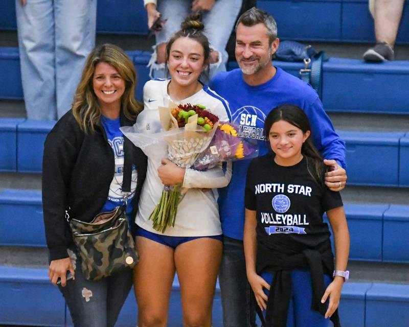St. Charles North's Haley Burgdorf, center, takes a second during a timeout in the game to take a photo with her parents Jill and Ken, along with sister Jocelyn, 11, after Haley made her 1,000 career kill during the game on Wednesday Oct. 2, 2024, while traveling to take on St. Francis High School in Wheaton.
