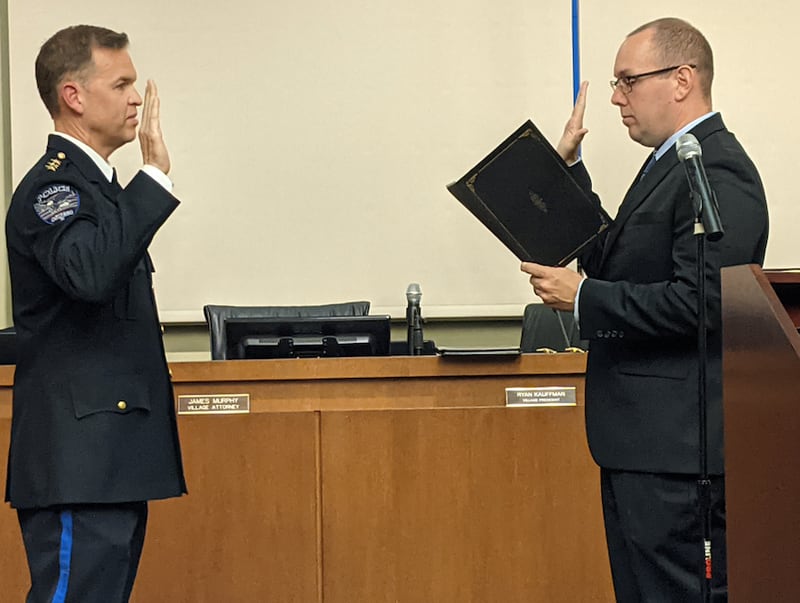 Oswego Village President Ryan Kauffman, right, swears in Jason Bastin, left, as the village's new police chief.