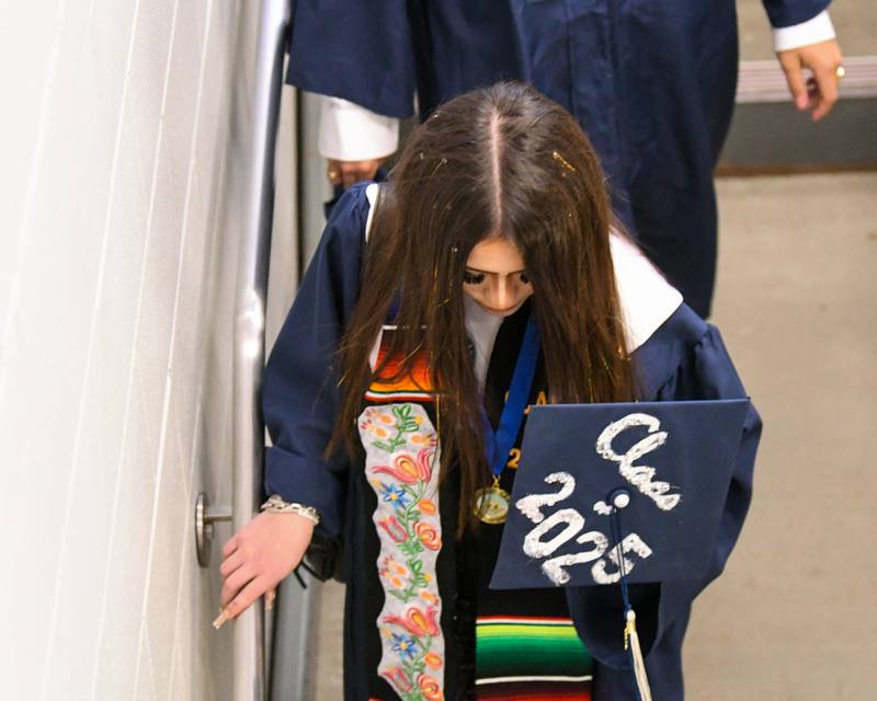 An Oswego East graduate make her way inside the Convocation Center in Dekalb on Saturday May 17, 2025, to line up before the start of the commencement ceremony.