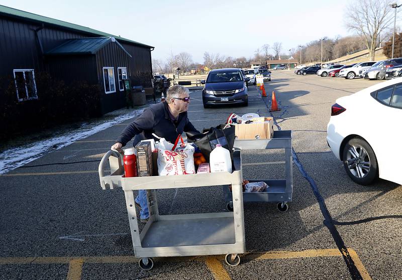 Volunteer Rich Meyers wheels out carts of food to a recipient’s car Tuesday, Jan. 10, 2023, at the FISH of McHenry Food Pantry, 3515 N. Richmond Road in Johnsburg. The pantry, which has changed how it distributes food since the COVID-19 pandemic, is now raising $150,000 to add more storage and a heated garage onto the building.