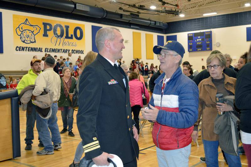 U.S. Navy Lt. Cmdr. Rick Knutson, left, of Polo, speaks to retired Navy Seaman 1st Class Tom Nelson, of Polo, at the end of a Nov. 11 Veterans Day ceremony at Centennial Elementary School. More than 100 people attended the event, in addition to students and staff. Knutson has served in active and reserve duty since 1998; Nelson served from 1965-69.
