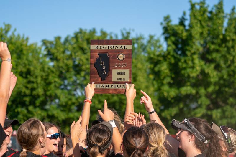 Yorkville softball players raise the 4A regional championship plaque after defeating Plainfield North for the class 4A regional championship at Yorkville High School on Friday, May 26, 2023.