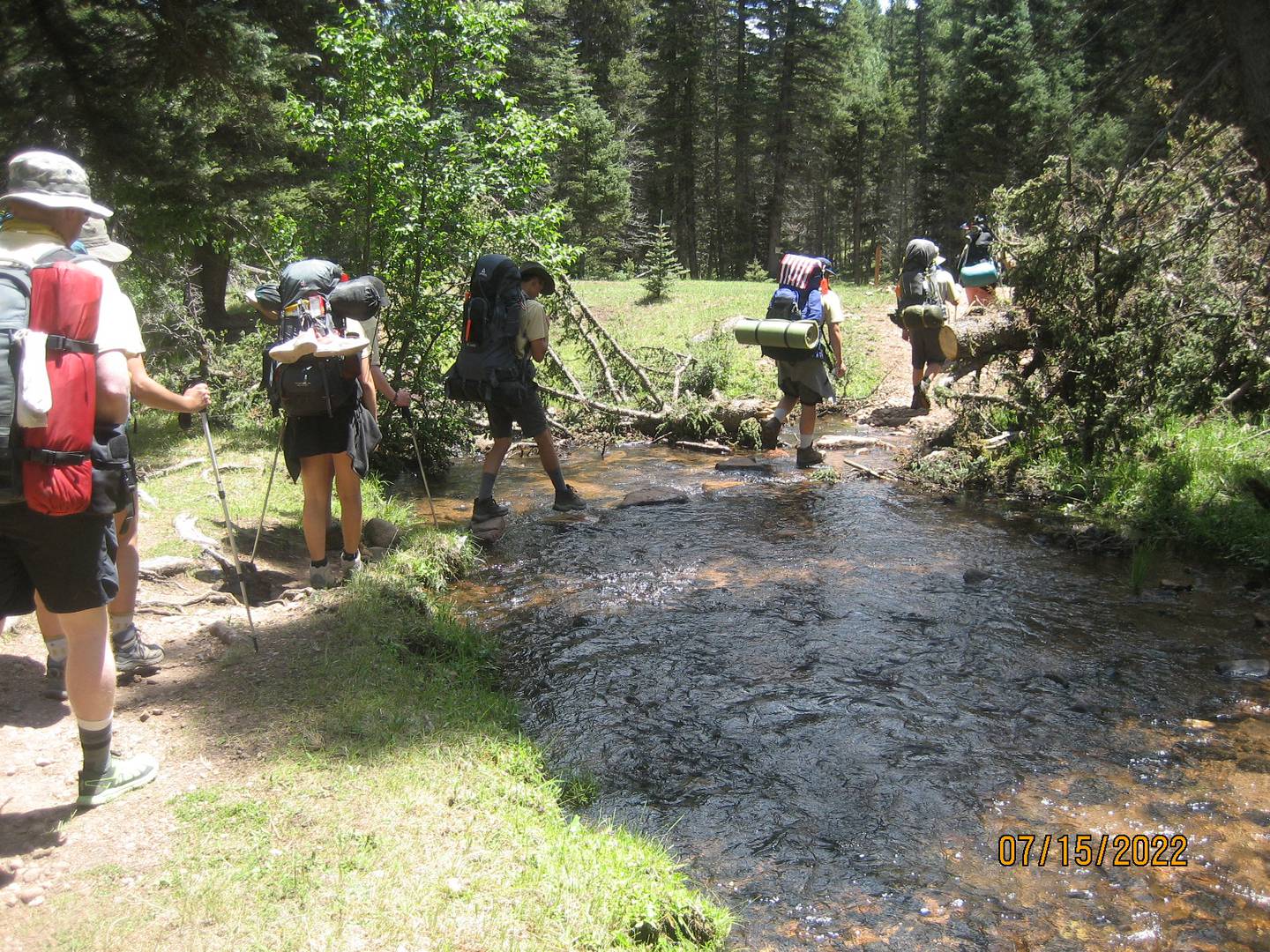Boy scouts from Waltham troop #797 hike across a stream with their camping gear