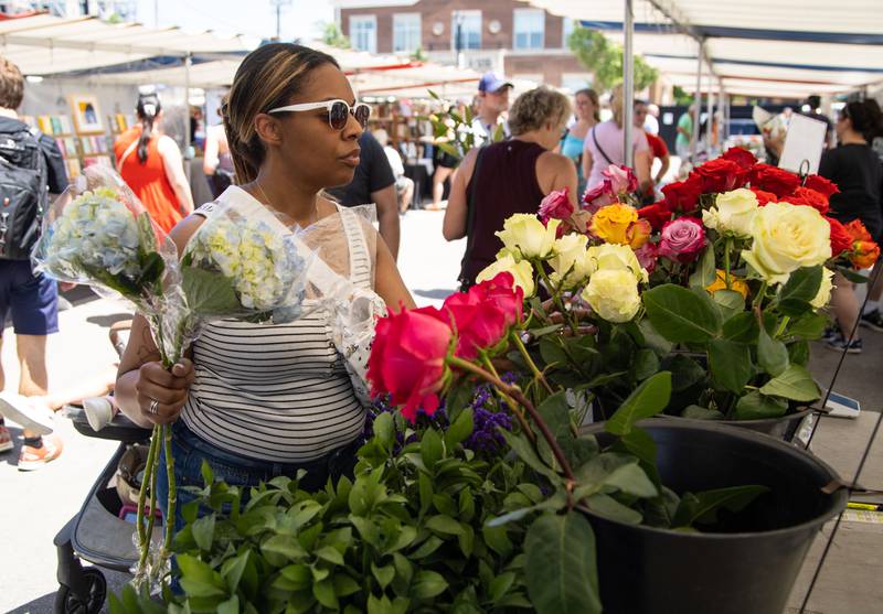 Danielle Levinson of Naperville purchases flowers during Make Music Wheaton and the Wheaton French Market in The Wheaton French Market Plaza on Saturday, June 21, 2025.