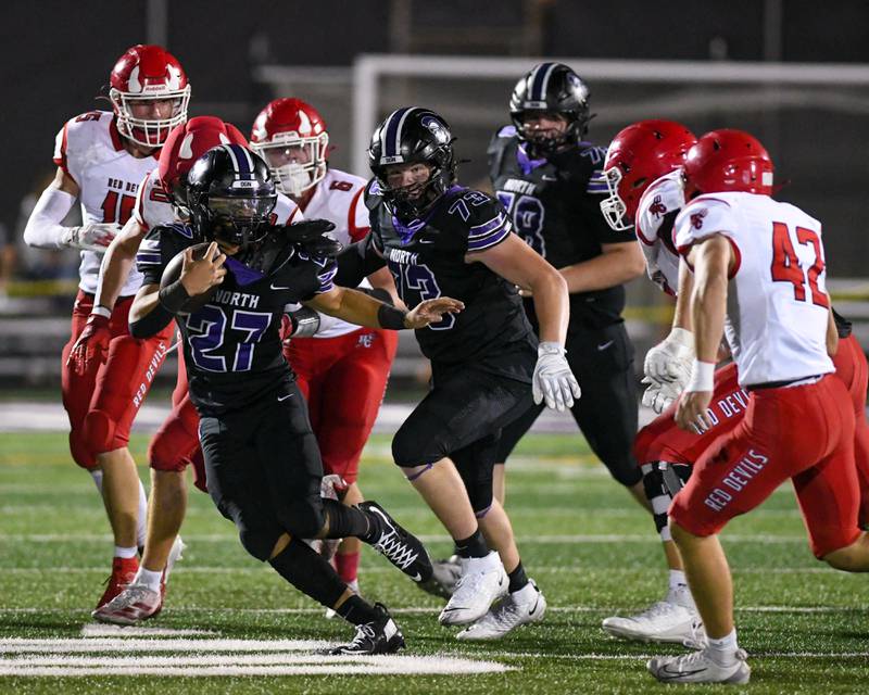 Downers Grove North's Kevin Jay Jr. (27) runs the ball before being brought down by Hinsdale Central defenders on Friday Sept. 12, 2025, held at Downers Grove North High School.