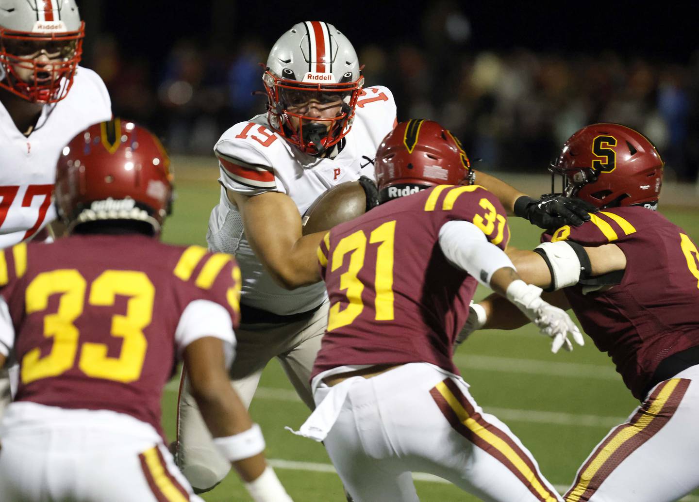 Palatine's Ray Gaspard (19) looks for a gap between Schaumburg's Sean Rogers (33) Rocco Fontela (31) and Ryan Much (8) Friday, Sept. 27, 2024 in Schaumburg.