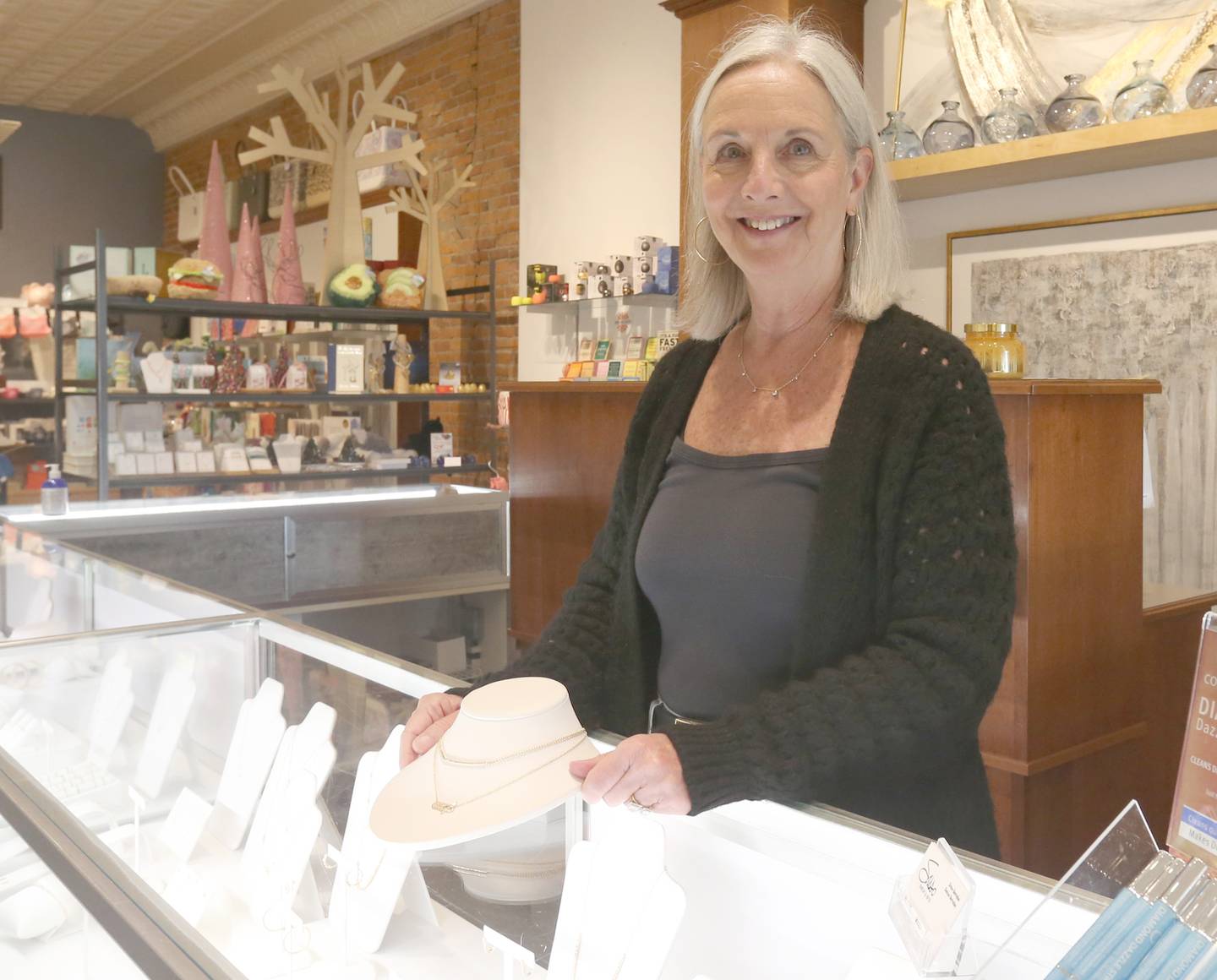 Denise Bernabei, owner of Sasso Jewelry and Gifts, poses for a photo with a necklace on Tuesday, Nov. 7, 2023. Fourth-quarter sales at local small businesses are on the rise throughout the Illinois Valley.