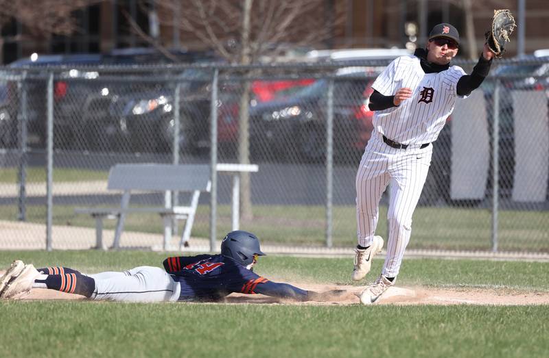 DeKalb's Paul Kakoliris has to come off the bag to make a play on a pickoff attempt as Naperville North's Trey Stade dives back in Tuesday, April 15, 2025, during their game at DeKalb High School.