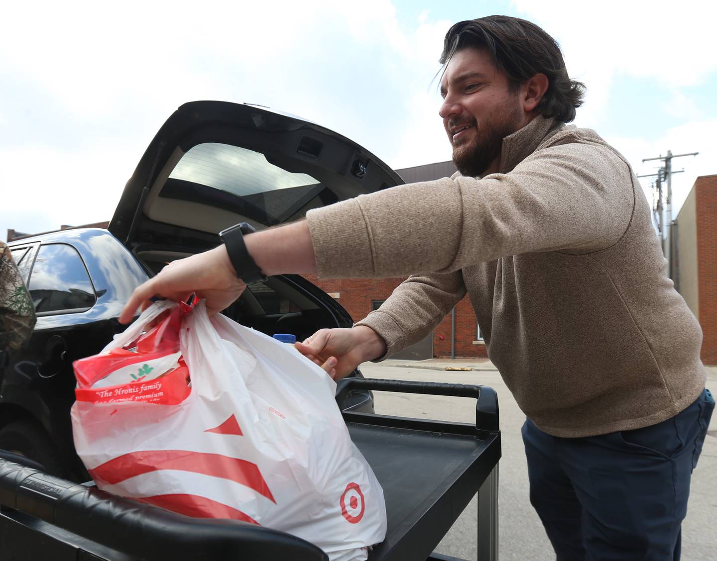 Bill Zens, executive director with the Illinois Valley Chamber of Commerce places a bag of food into a trunk of a vehicle during the Christmas distribution on Wednesday, Dec. 18, 2024 at the Illinois Valley Food Pantry in La Salle.