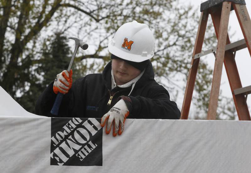 McHenry High School student David May installs weather wrap on a tiny shop being constructed Monday, May 1, 2023, at the new McHenry Riverwalk Shoppes at Miller Point Park in McHenry. McHenry High School students joined volunteers from Habitat for Humanity of McHenry County, McHenry Parks and Recreation Department staff, and contractors to build the shops at the site.