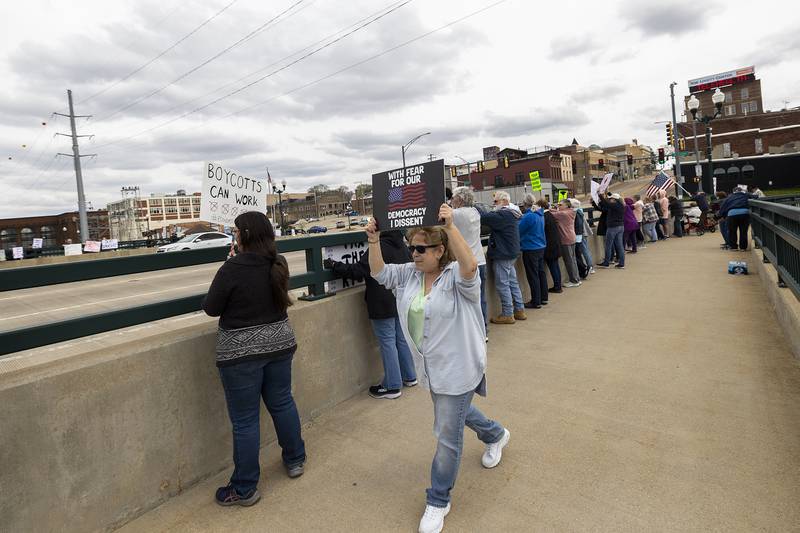 Protestors line the edges of the Galena Avenue bridge in Dixon Saturday, April 19, 2025, voicing their opinion of President Trump and their feelings the administration is not following a Democracy based government.