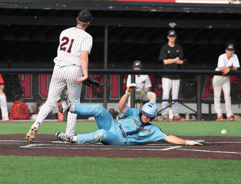 Marquette's Alec Novotney scores on a wild pitch as Fulton's Chase Dykstra covers home Monday, June 2, 2025, during their Class 1A supersectional game at Northern Illinois University in DeKalb.