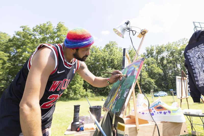 Sam Katz of Plano does some painting Friday, July 12, 2024 at Herbal Roots’ Cannafest at Elks Page Park. Katz makes works of art on canvas of all kinds, including sneakers.