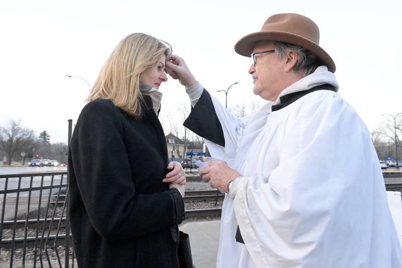 Ewa Duranodic of North Aurora receives a traditional blessing of a cross of ash on her forehead from Lee Kolodziej of St. Charles Episcopal Church at the Geneva train station on Wednesday, Feb 18, 2026.