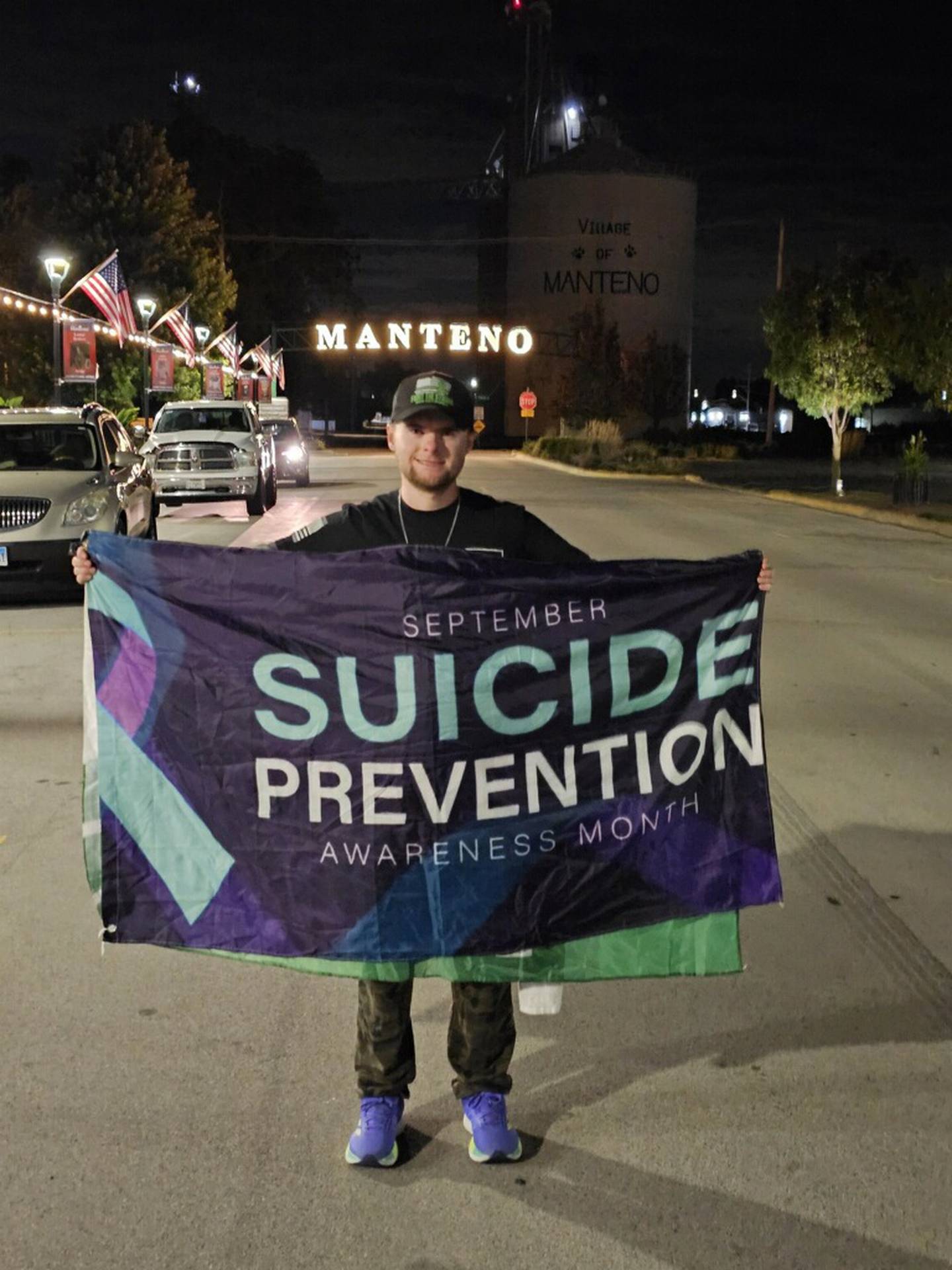 Manteno resident Jake Smith, 28, stands with a flag for Suicide Prevention Awareness Month during his annual mental health awareness walk on Saturday, Sept. 6, 2025.