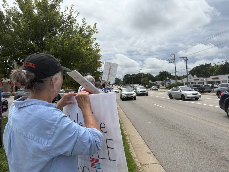 Protesters hold up signs during a protest in McHenry July 26, 2025.