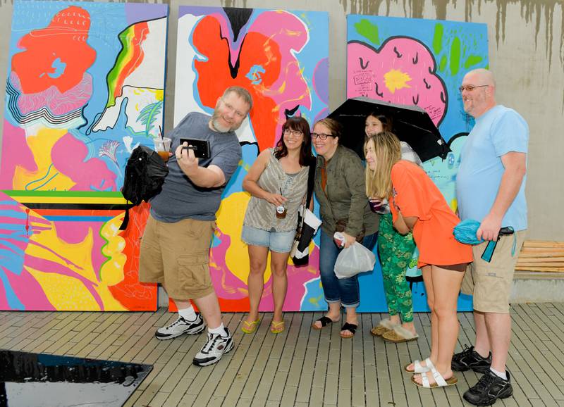 A group takes a selfie in front of a art piece during the Fine and Cultural Arts Commission’s Andy Warhol’s birthday at the Wheaton French Market on Saturday, August 5, 2023.