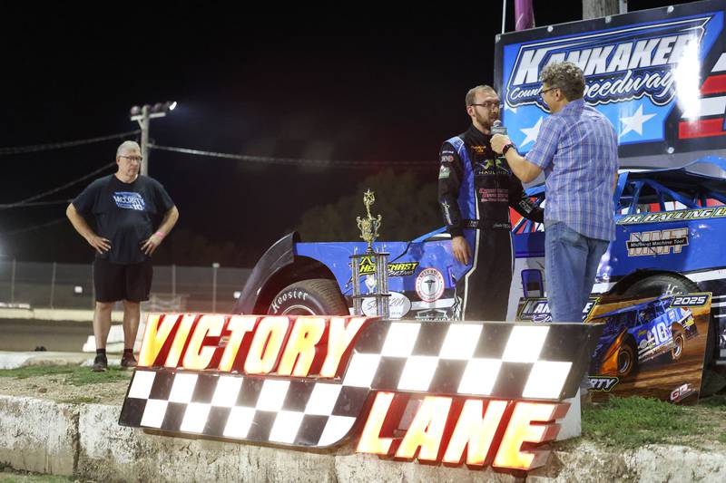 Austin McCarty, center, interviews with announce Bill Yohnka as his father, Steve, looks on while he is awarded the Pro Late Model class champion trophy on Friday, Sept. 26, 2025, at the Kankakee County Speedway. McCarty won the title for the second year in a row, earning the McCarty family's 10th overall title following a bittersweet racing season.