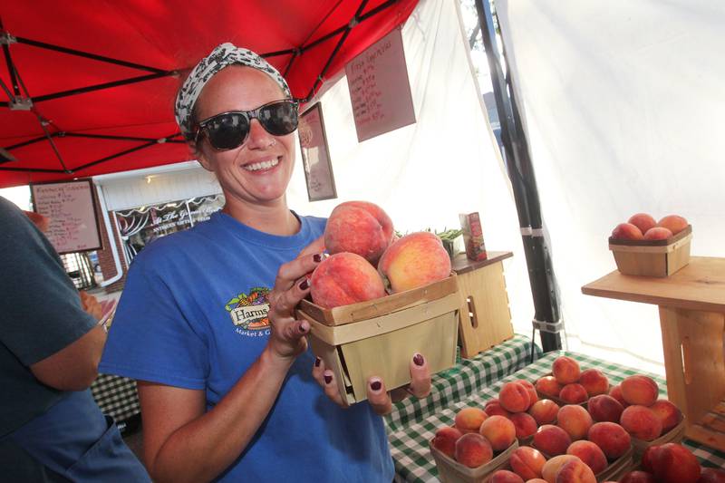 Lauren Babineau, of McHenry, farm hand with Harms Farm Market & Garden Center, shows the Michigan peaches that are a fan favorite in the produce stand at the Wauconda Farmers’ Market in downtown Wauconda. The farmers’ market runs on Thursday afternoons from 4-7pm through September 29th